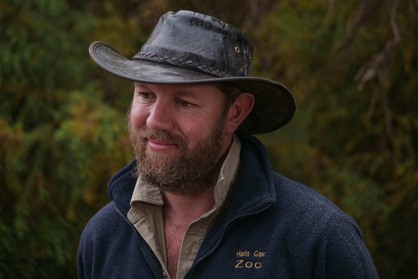 a man in a leather wide brim hat smiles