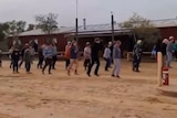 A bunch of people dance out the front of an outback pub
