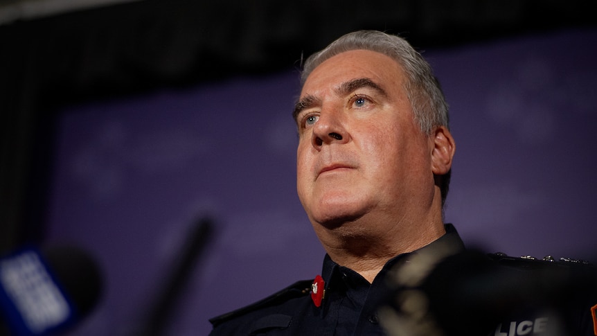 NT Police Commissioner Michael Murphy standing at a lectern and looking up.