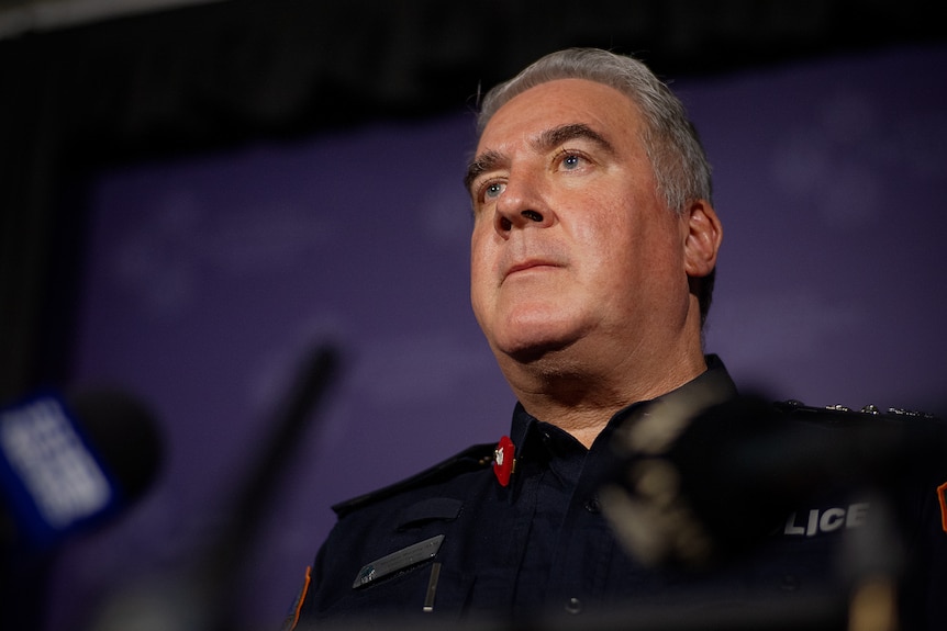 NT Police Commissioner Michael Murphy standing at a lectern and looking up.