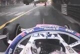 View from the top of Sergio Perez' formula one car as he drives towards two men who are walking on the track