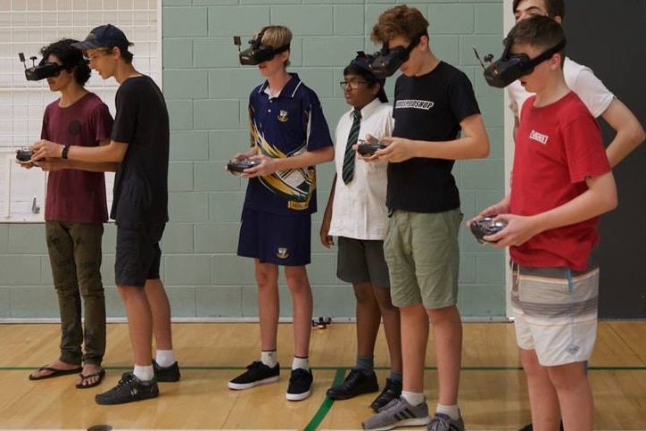 Teenagers wear VR headgear to race drones