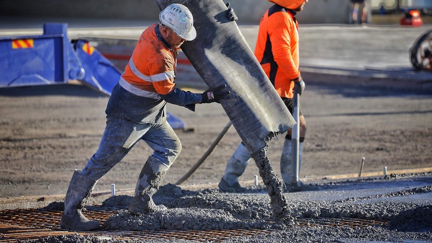 A worker pours concrete at a building construction site in Brisbane.