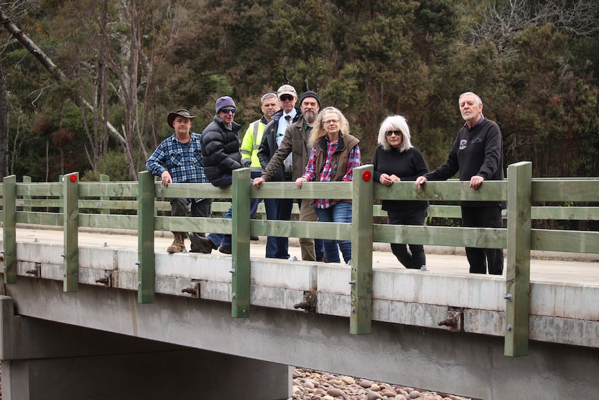 A group of people stand on a bridge together.