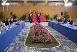 groups of people sat at two long blue tables with flowers and Australian and Chinese flags in the middle