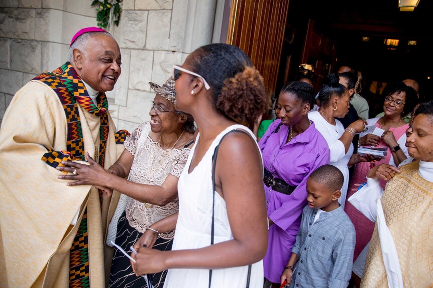 Archbishop Wilton Gregory greets parishioners at the front of St Augustine Church after mass.