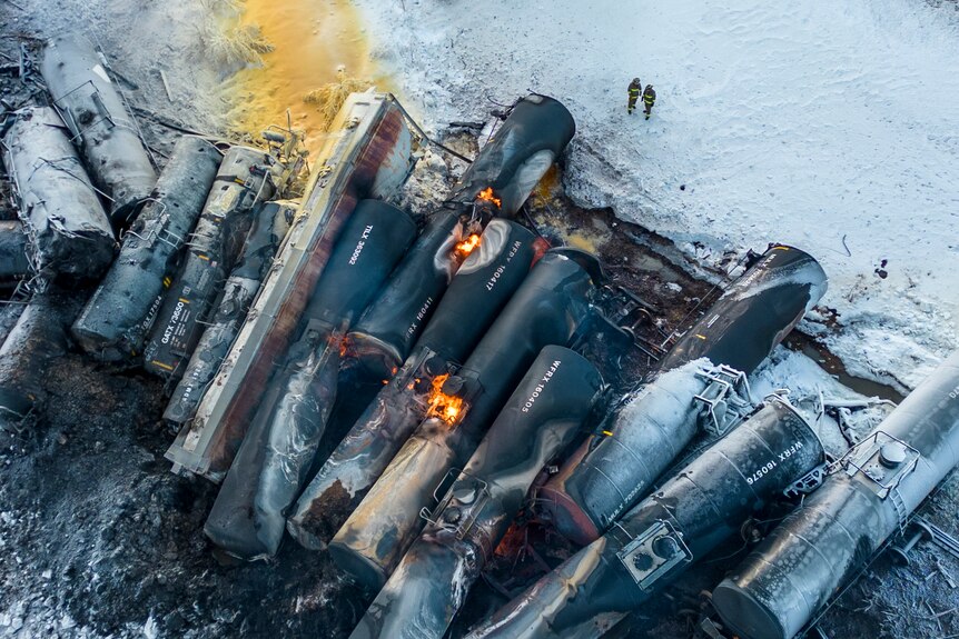 Burnt train cars piled next to each other in the snow.