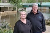 man and woman standing in front of flooded caravans 