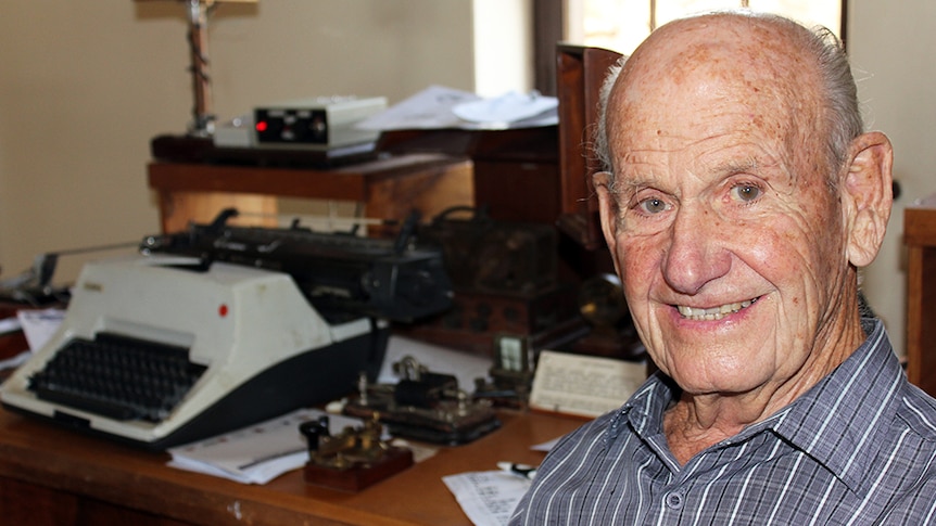 An elderly man sits in front of a Morse code device at the Alice Springs Telegraph station.
