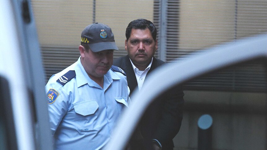 Adeel Khan is escorted by Corrective Services officers to a prison transport van.