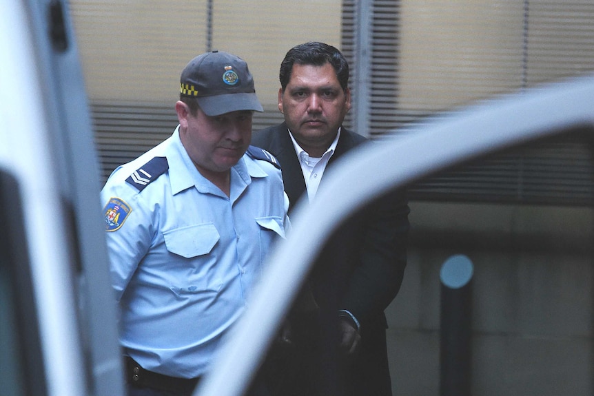 Adeel Khan is escorted by Corrective Services officers to a prison transport van.