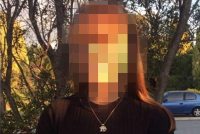 An amateur photo of a girl with a black top and necklace in front of trees with her face pixellated.