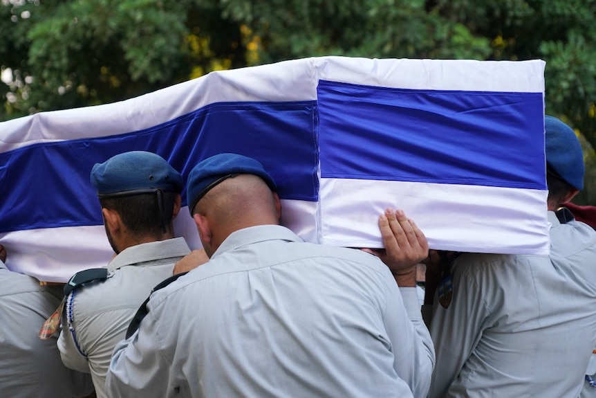 Several soldiers in uniform carrying a coffin with a flag draped over it
