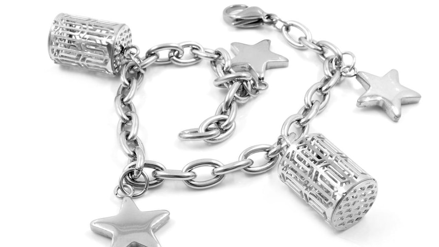 A silver chain bracelet with several charms attached including a star and a basket.