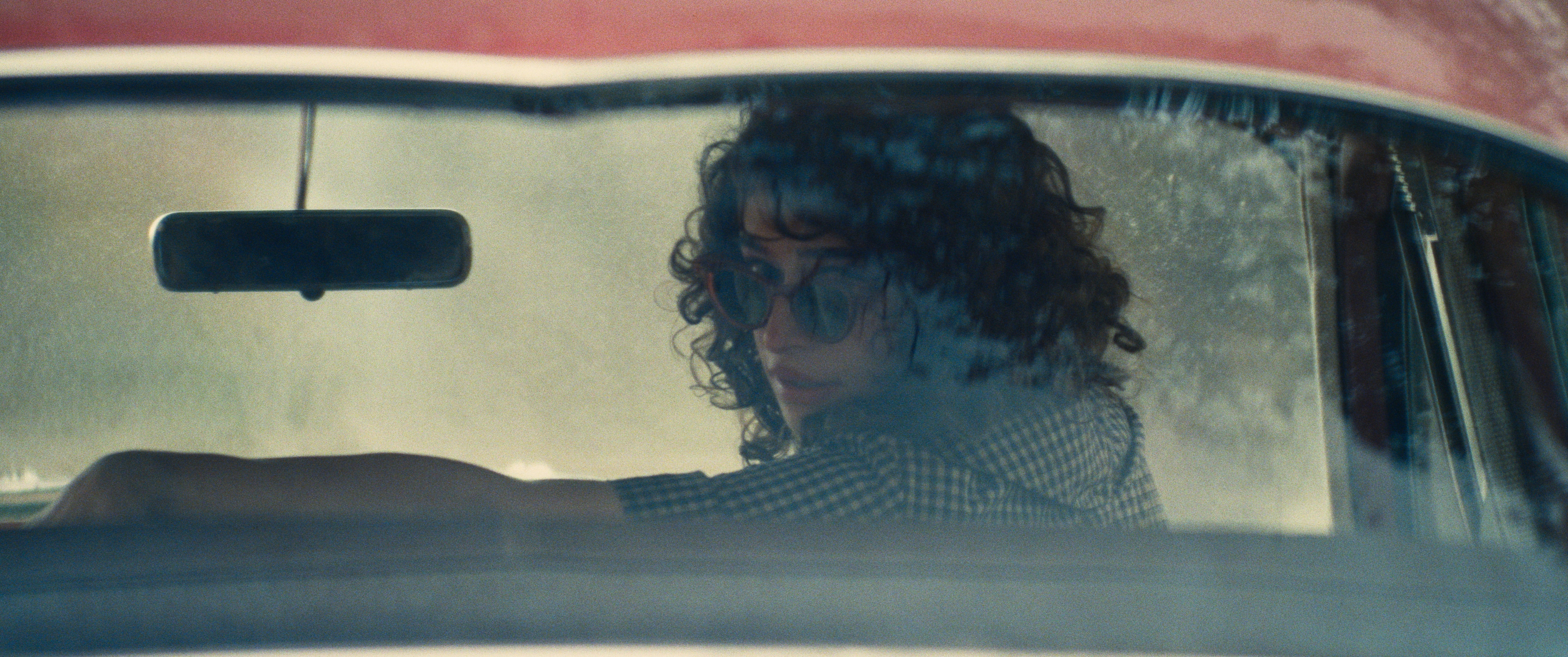 Una mujer con gafas de sol mira por la ventanilla trasera de un coche