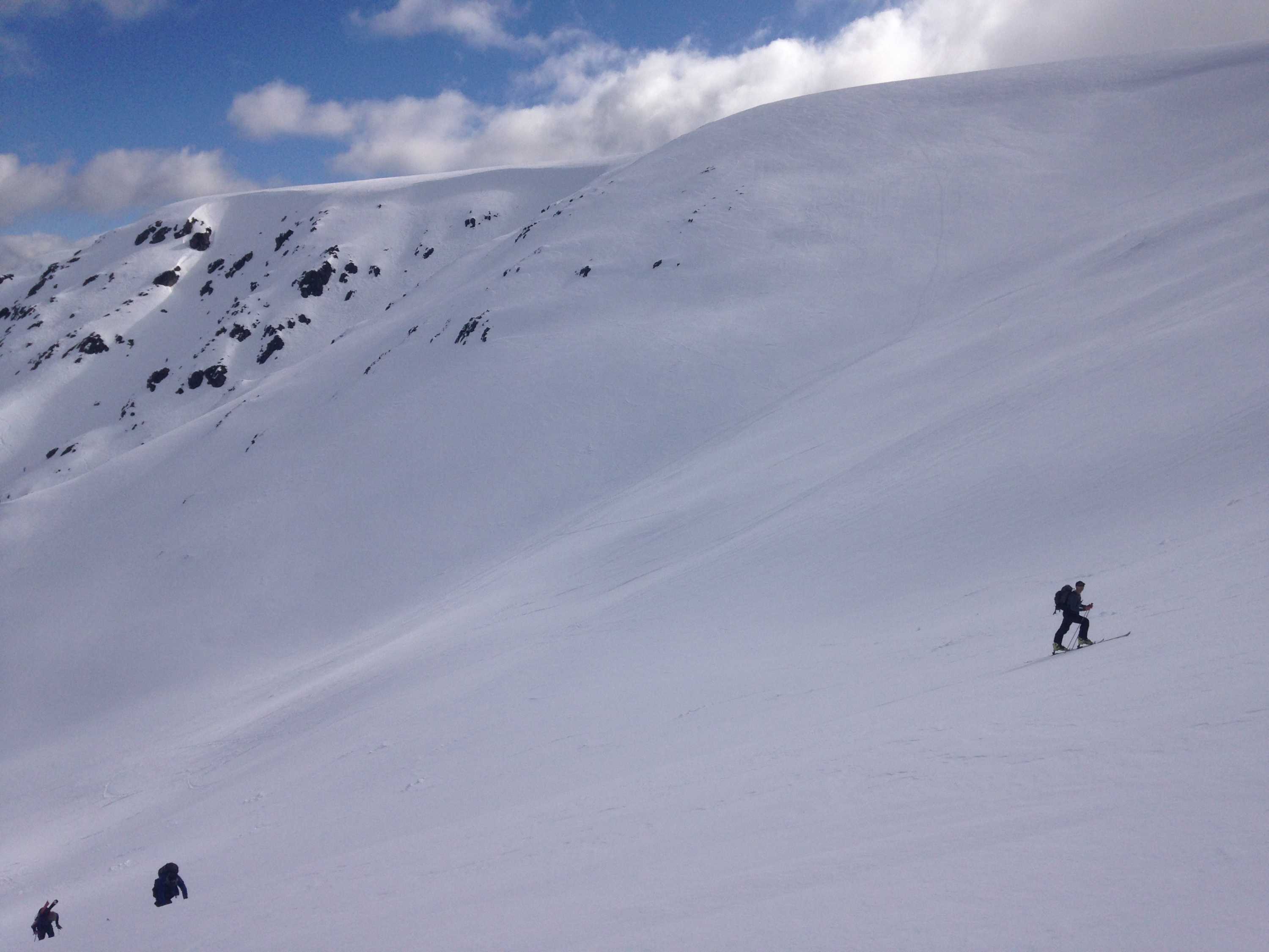 Skiers work their way up a snow-covered mountain.