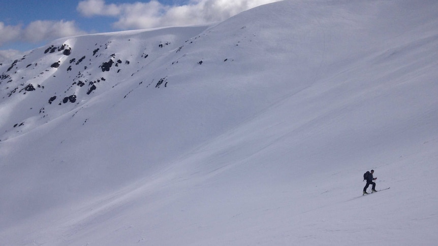 Skiers work their ways up a snow-covered mountain.