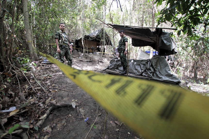 Security forces are seen at an abandoned camp in a jungle.