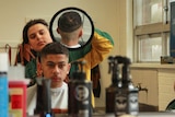 Mohomed Hamdan holds a mirror behind a 'customer', to enable him to check the back of his hair.
