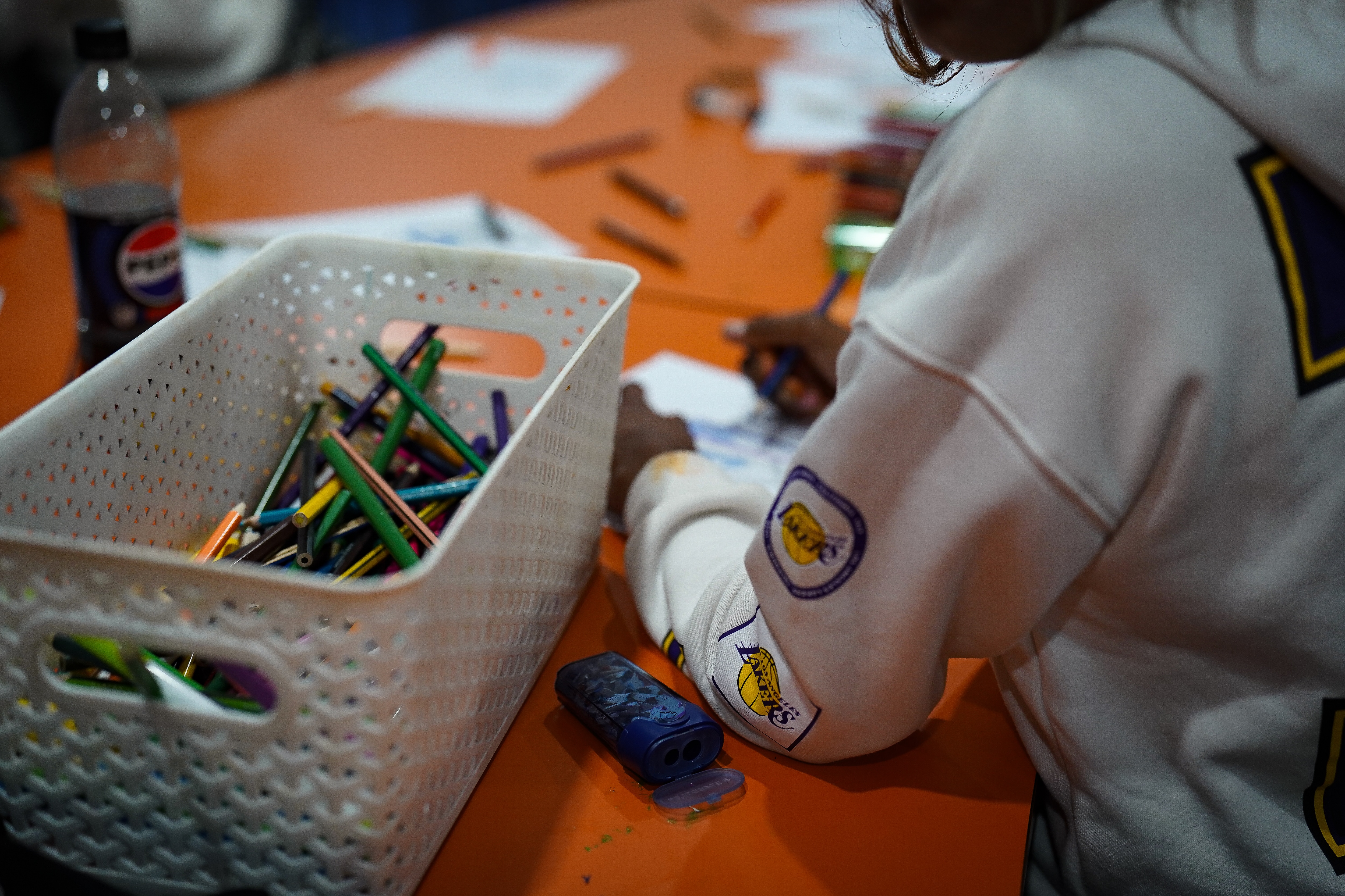An Indigenous child sits at a table with paper and coloured pencils.