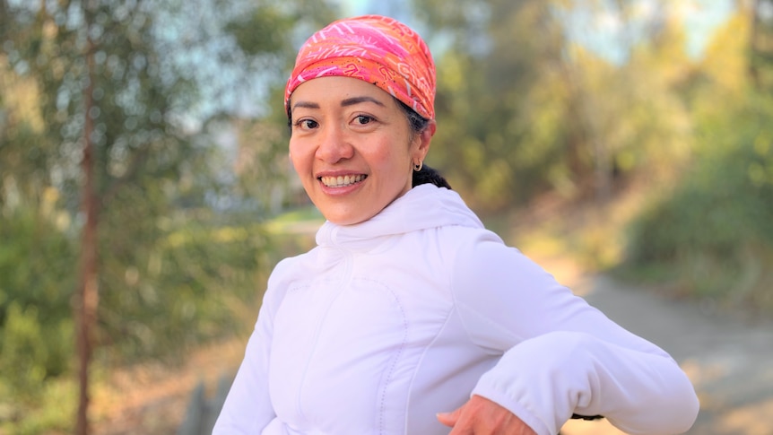 A woman smiling and sitting on a bench at a park in Melbourne