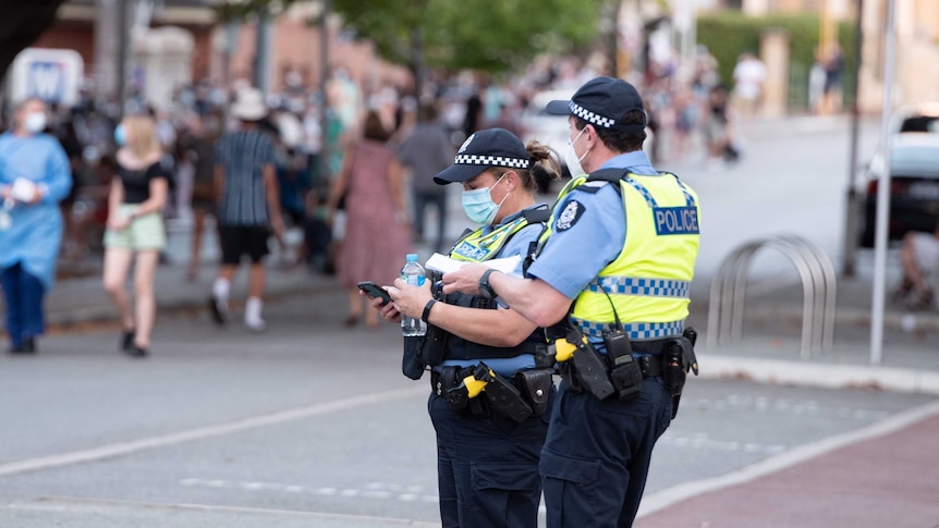 Police wear facemasks in front of a line of people wearing masks.