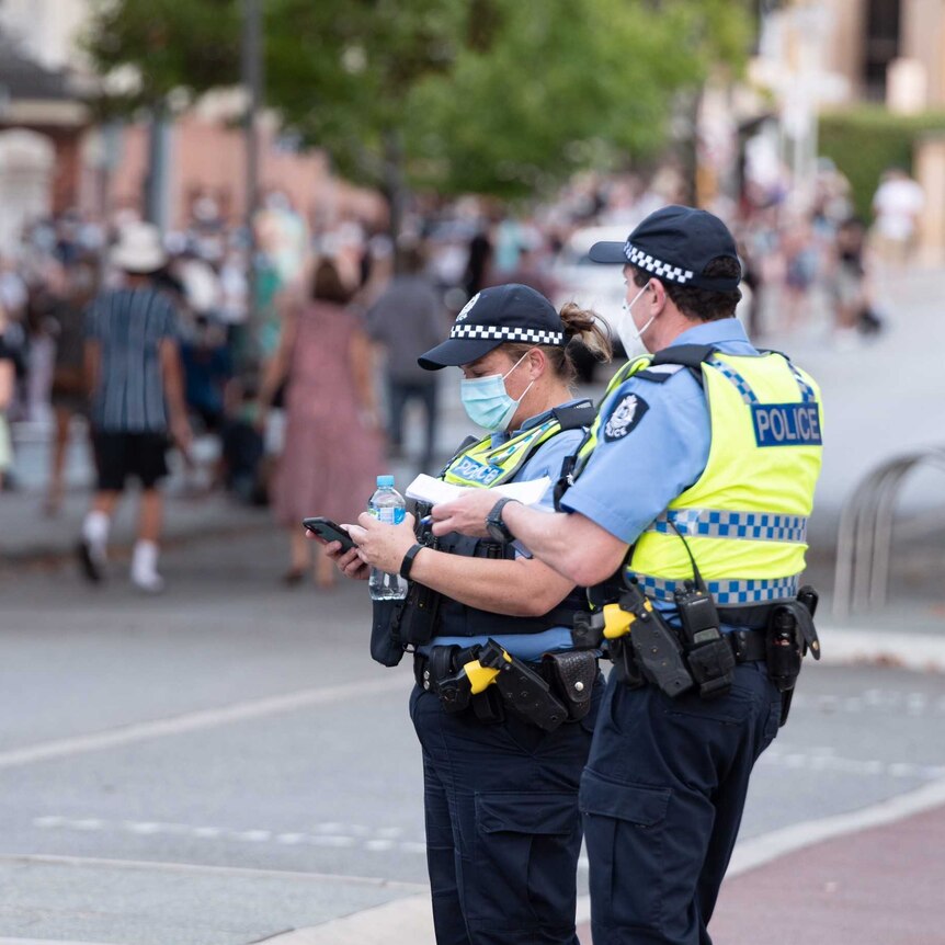 Police wear facemasks in front of a line of people wearing masks.