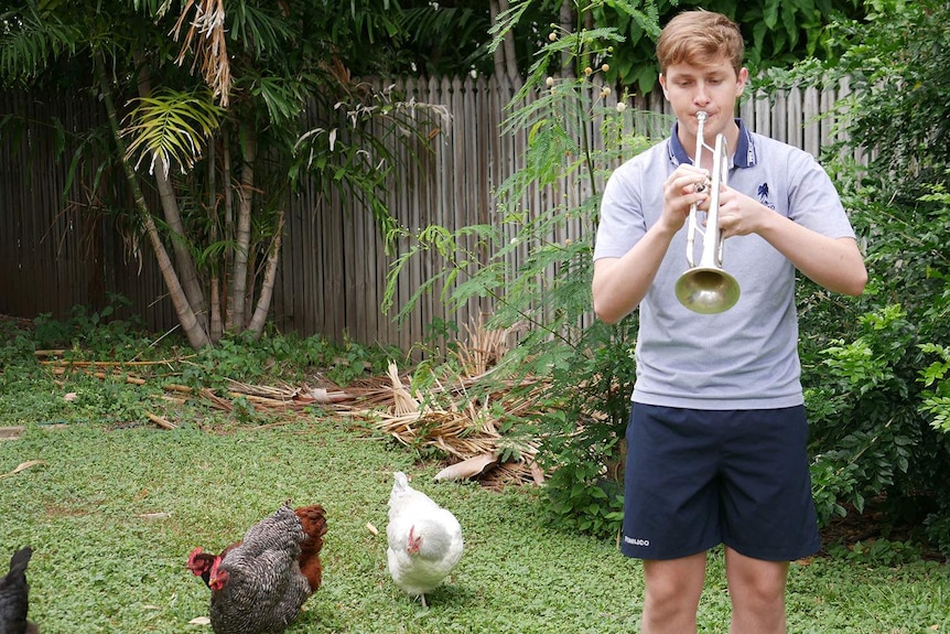 Max Robson practising the trumpet in the backyard at his house with the chickens.