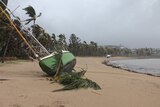 Two boats are toppled over in the sand at airlie beach