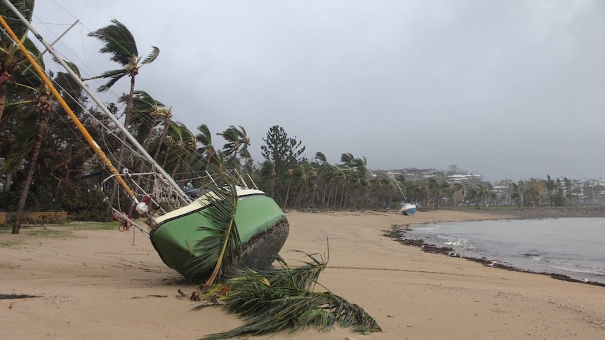 Two boats are toppled over in the sand at airlie beach