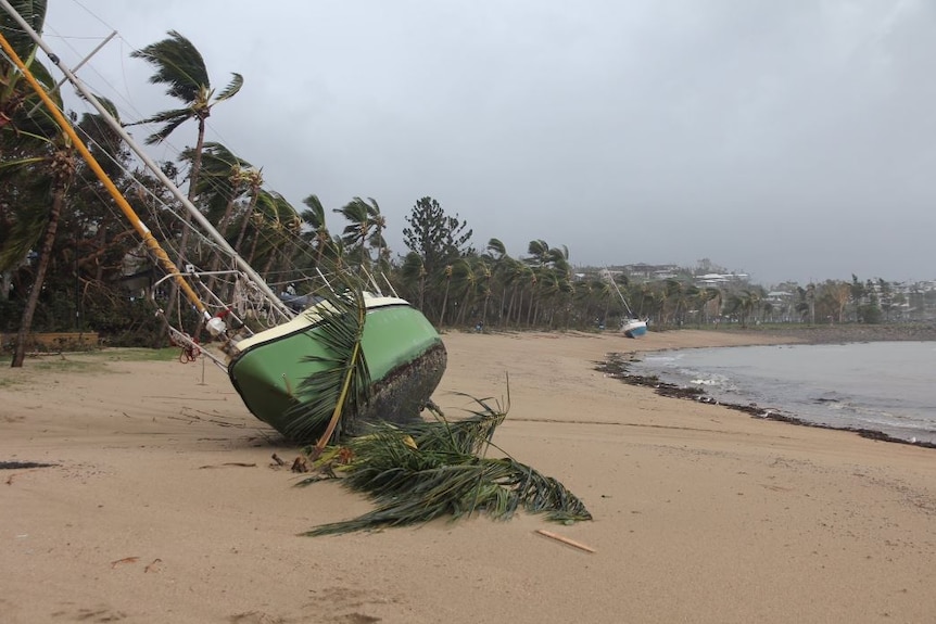 Two boats are toppled over in the sand at Airlie Beach