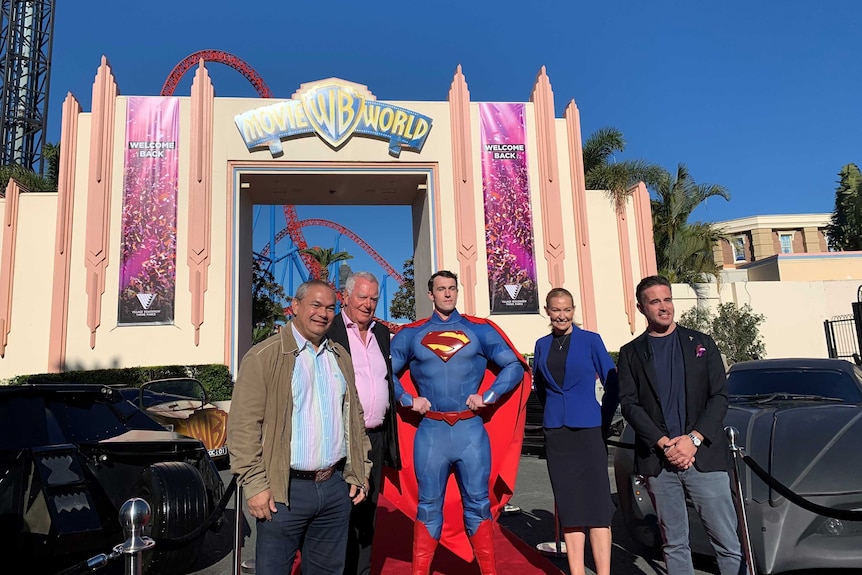 Tom Tate stands outside Movie World on the Gold Coast with Superman and a group of people