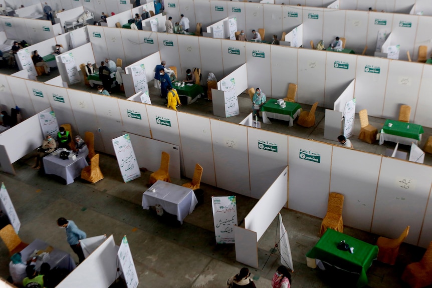 Senior citizens receive the Sinopharm coronavirus vaccine in cubicles as seen from an aerial view.