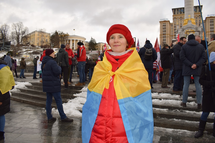 Une femme portant un chapeau rouge et un drapeau regarde au loin.