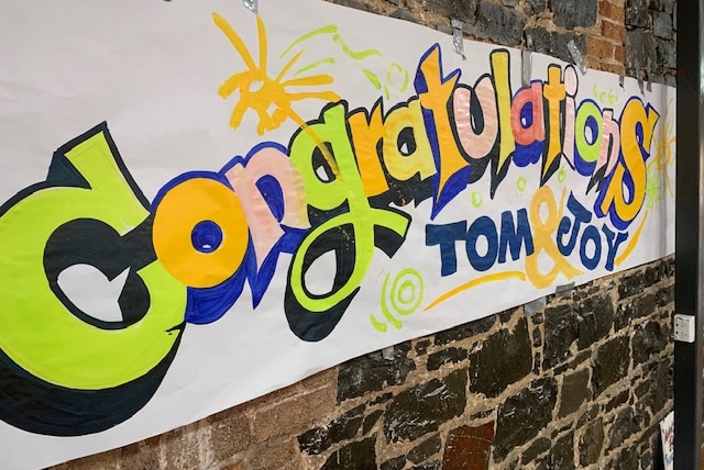 A hand painted sign that reads 'Congratulations Tom and Hoy'