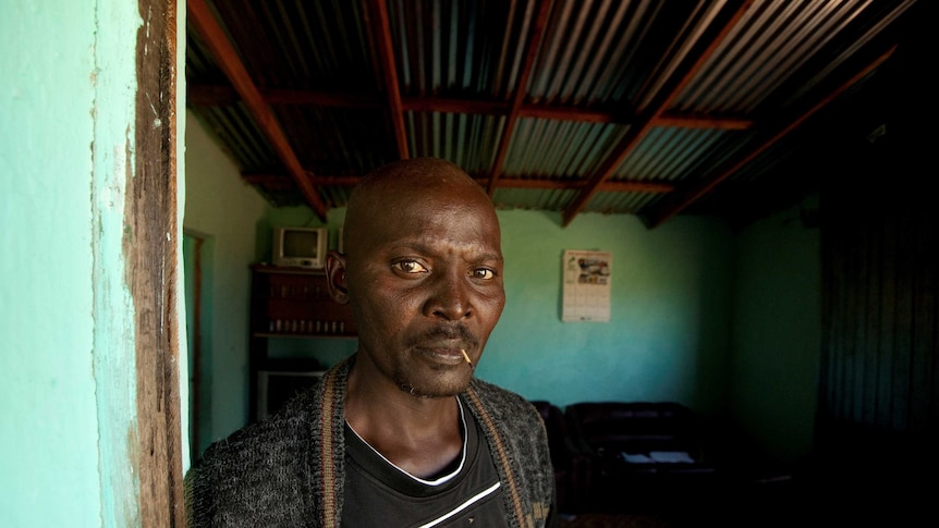 Former gold miner Thulani Bitsha, stands in the doorway to his home, chewing on a match.