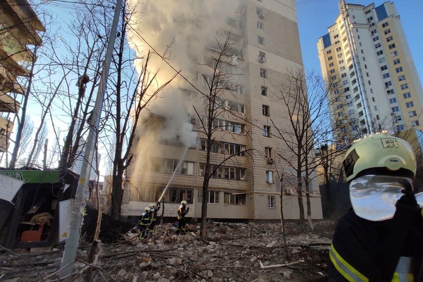 Fire fighters work on a building recently shelled by Russian forces