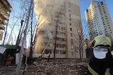 Fire fighters work on a building recently shelled by Russian forces