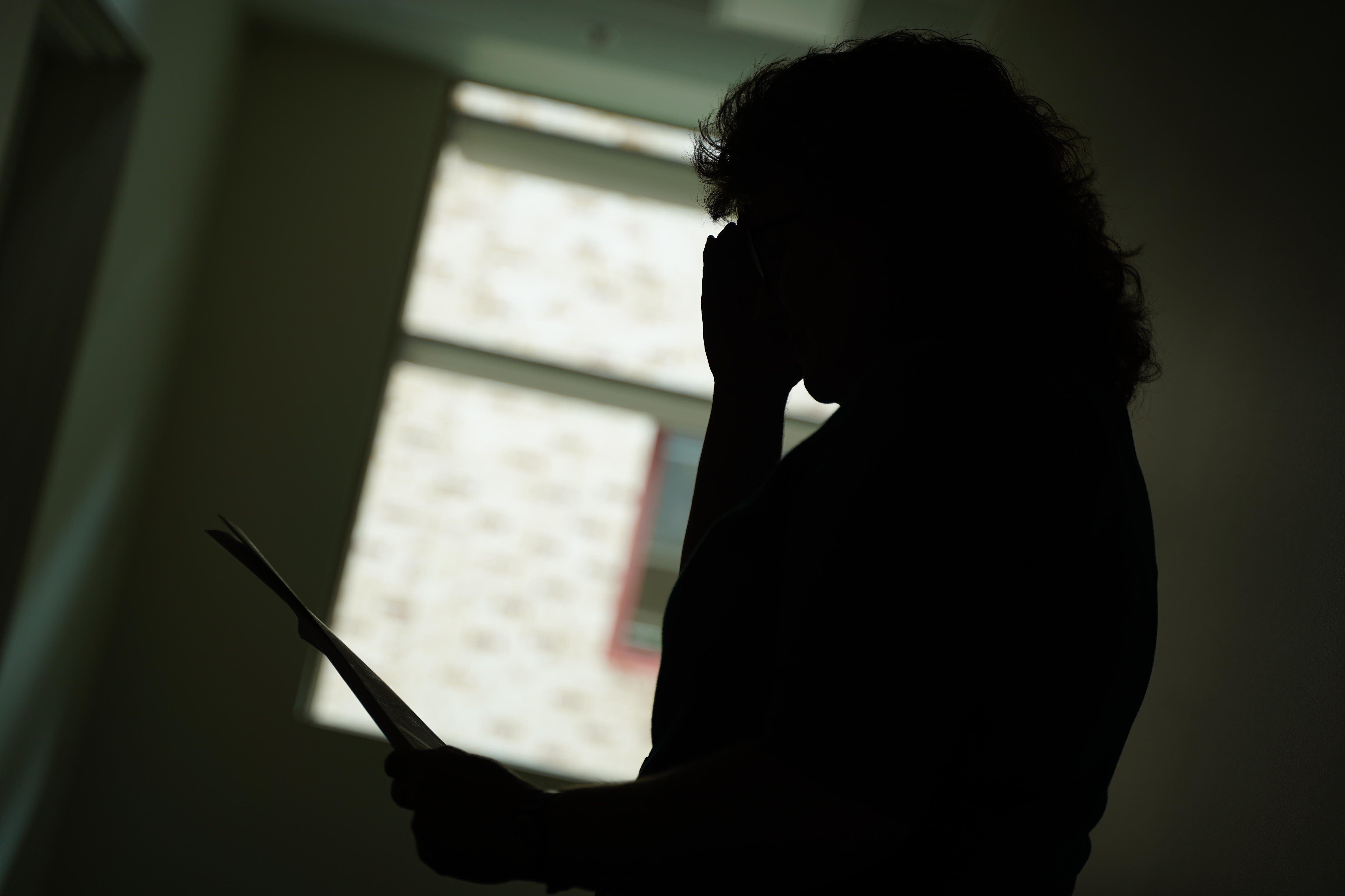 The silhouette of a woman holding papers. 