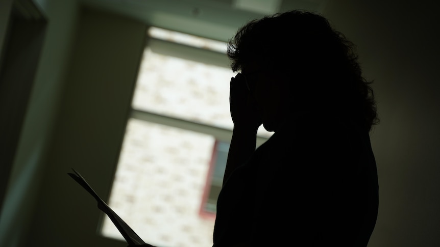 The silhouette of a woman holding papers. 