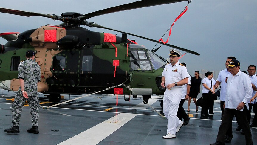 President Rodrigo Duterte walks past a helicopter during a tour on board HMAS Adelaide.