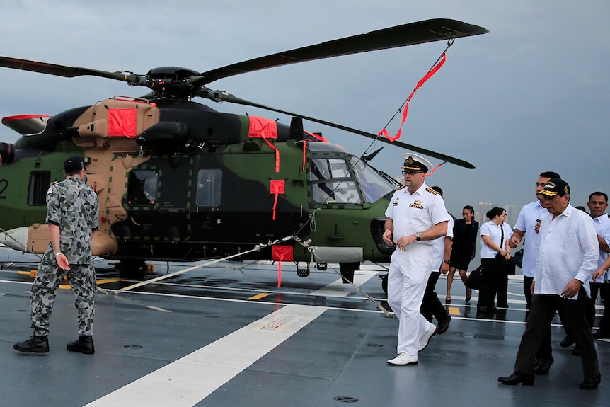 President Rodrigo Duterte walks past a helicopter during a tour on board HMAS Adelaide.