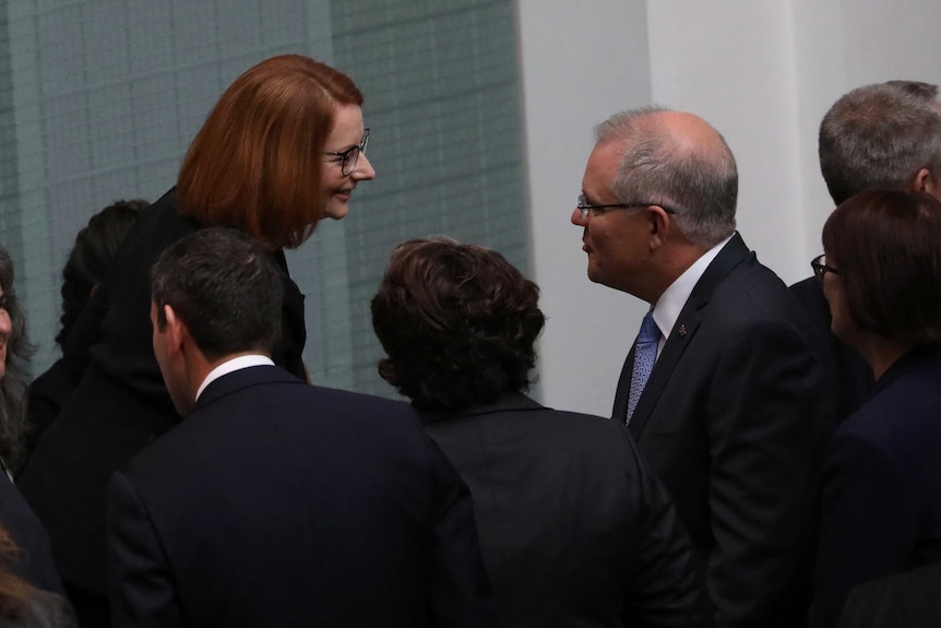 Ms Gillard is smiling at Mr Morrison, on the sideines of the House of Representatives.