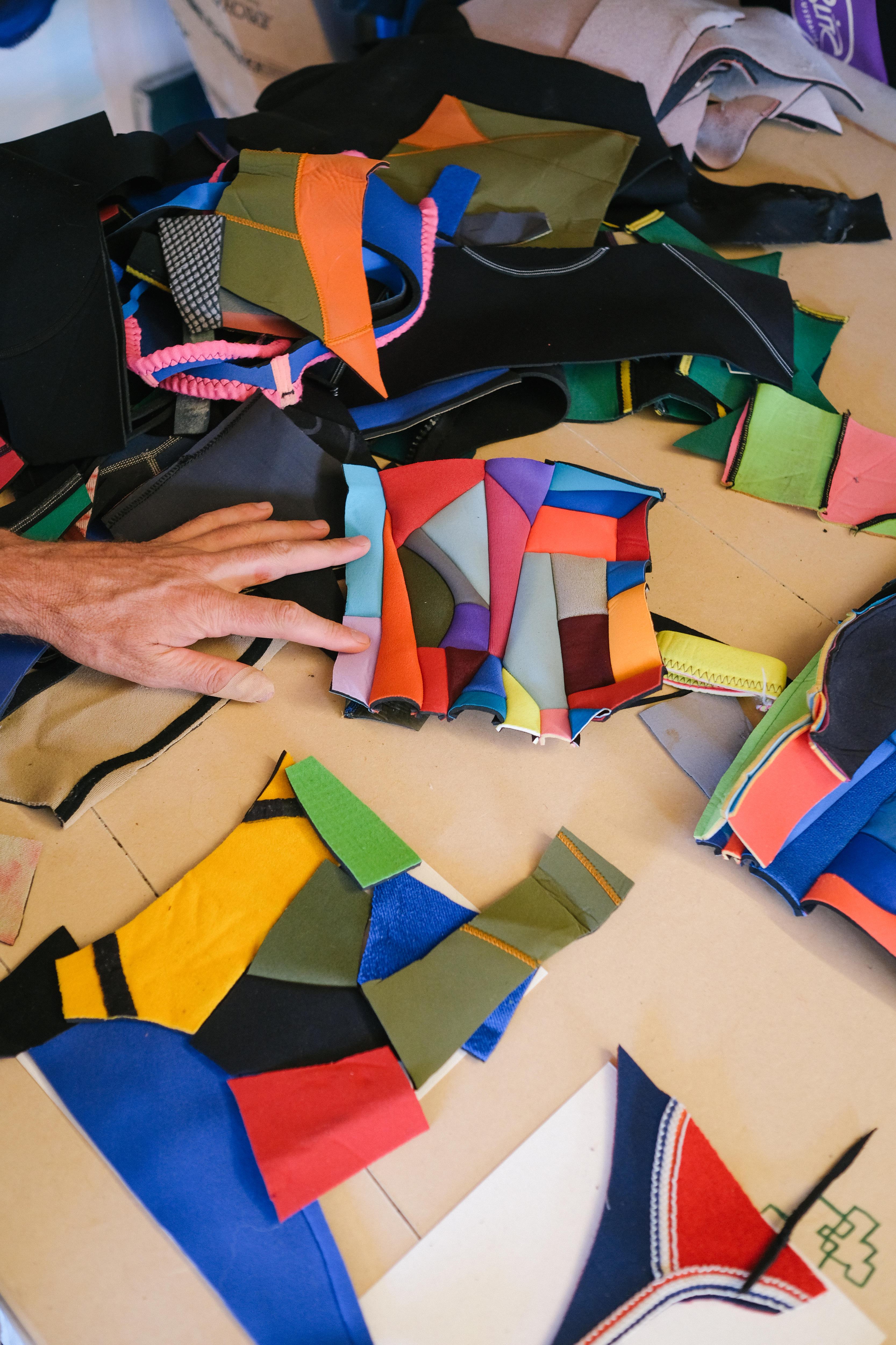 Close up of artist assembling shapes of neoprene on a table in his studio 