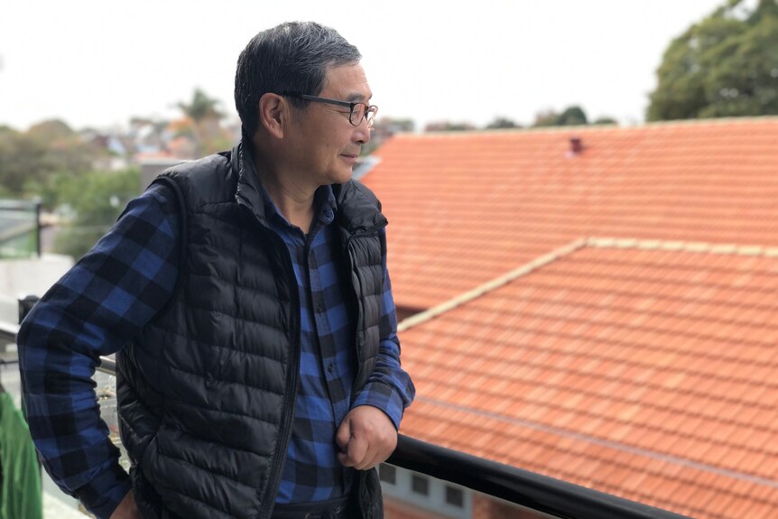 Zhang Tan looks out from his balcony at home in Australia.