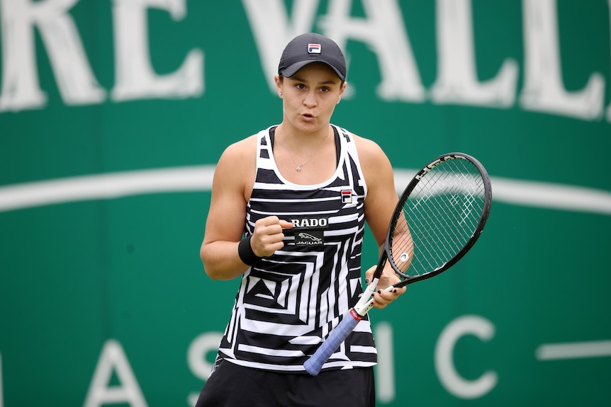 Ashleigh Barty clenches her fist while holding her racquet in the other hand