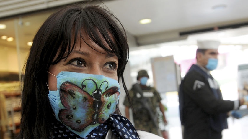 An employee of Mexicana Airlines wears a surgical mask with a butterfly painted on it