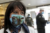 An employee of Mexicana Airlines wears a surgical mask with a butterfly painted on it