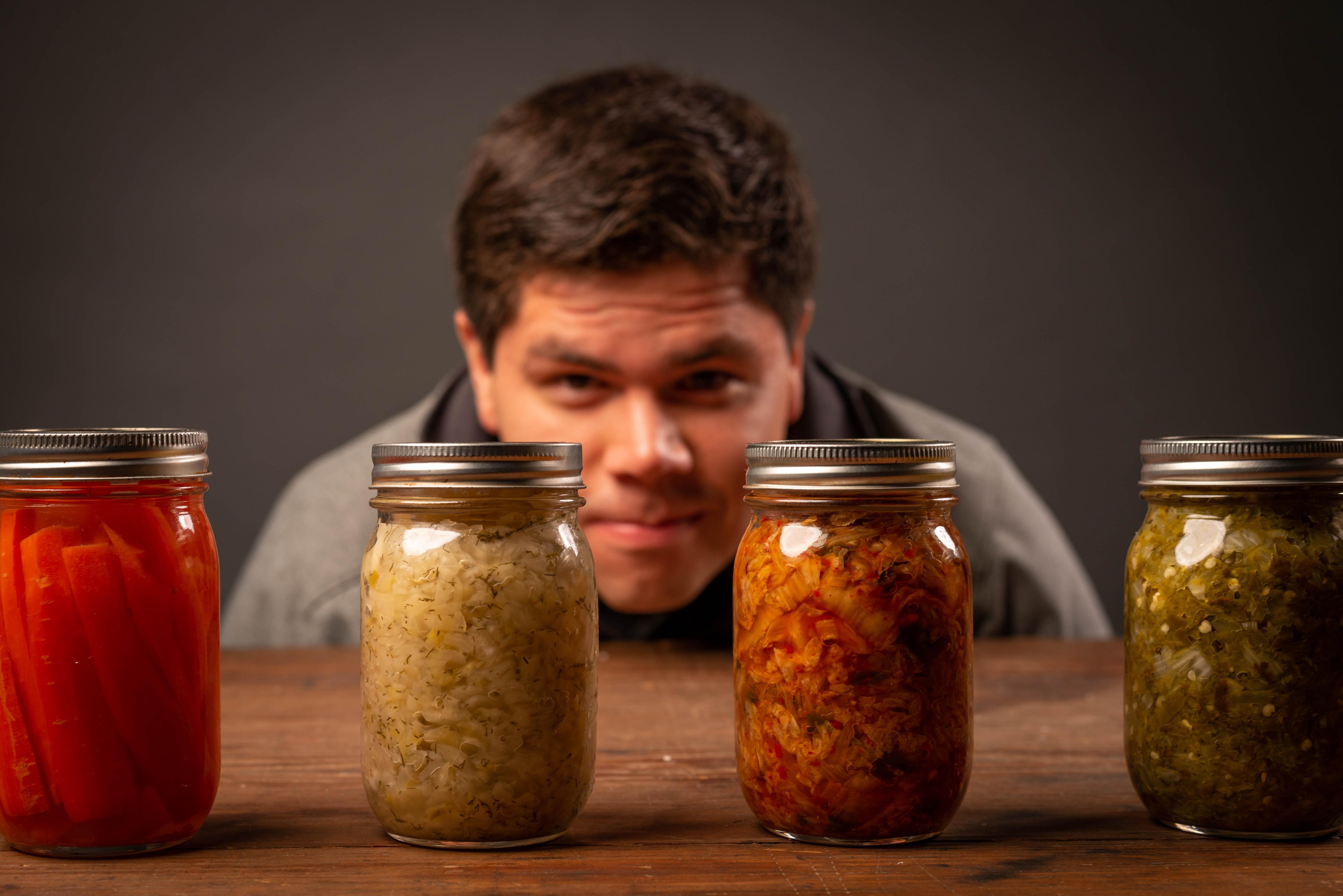 Jars of pickles and sauerkraut with a man in the background