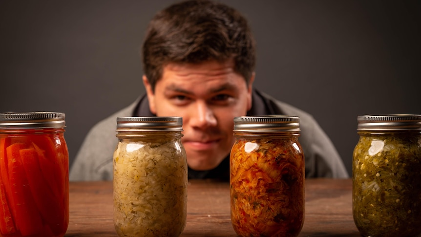 Jars of pickles and sauerkraut with a man in the background
